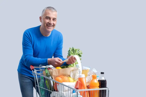 Smiling Man Leaning Full Shopping Cart Checking Grocery Receipt Offers — Stock Photo, Image