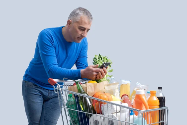 Uomo Spingendo Carrello Della Spesa Utilizzando Uno Smartphone Negozi Alimentari — Foto Stock