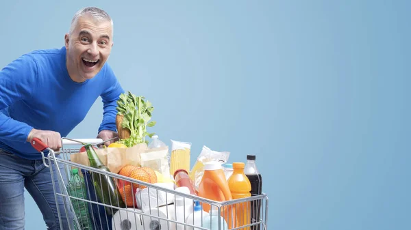 Sorridente Uomo Eccitato Spingendo Carrello Pieno Generi Alimentari — Foto Stock