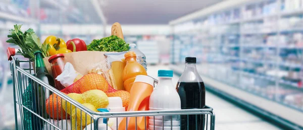 Winkelwagen Gevuld Met Eten Drinken Supermarkt Planken Achtergrond Boodschappenconcept — Stockfoto