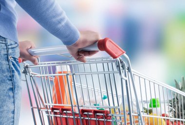 Markette alışveriş yapan bir kadın, bir alışveriş arabası itiyor, elini kapat.