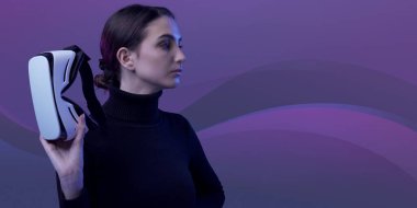 Çekici genç bir kadın, elinde bir VR kulaklığı tutuyor ve başka tarafa bakıyor, sanal gerçeklik ve metazıt konsept