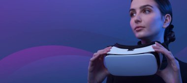 Elinde bir VR kulaklık tutan ve sanal gerçekliğe erişen genç bir kadın. Arka planda soyut dalgalar, metazet ve sanal gerçeklik kavramı.
