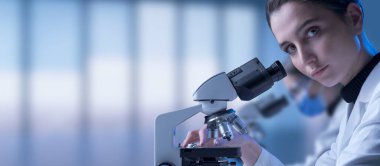 Genç bayan araştırmacı mikroskop kullanarak kamera, bilim ve tıbbi araştırma konseptine bakıyor.