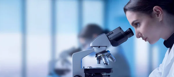 研究室で働いている若い研究者は 顕微鏡を通してサンプルをチェックし 医学研究の概念 — ストック写真