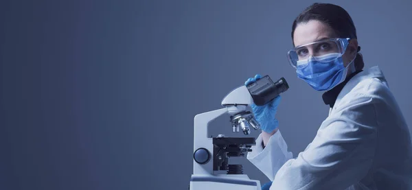 Onderzoeker Draagt Een Chirurgisch Masker Kijkt Met Een Microscoop Naar — Stockfoto