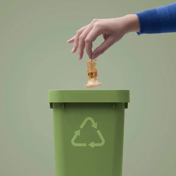 Woman putting biodegradable organic waste in a bin, recycling and waste segregation concept