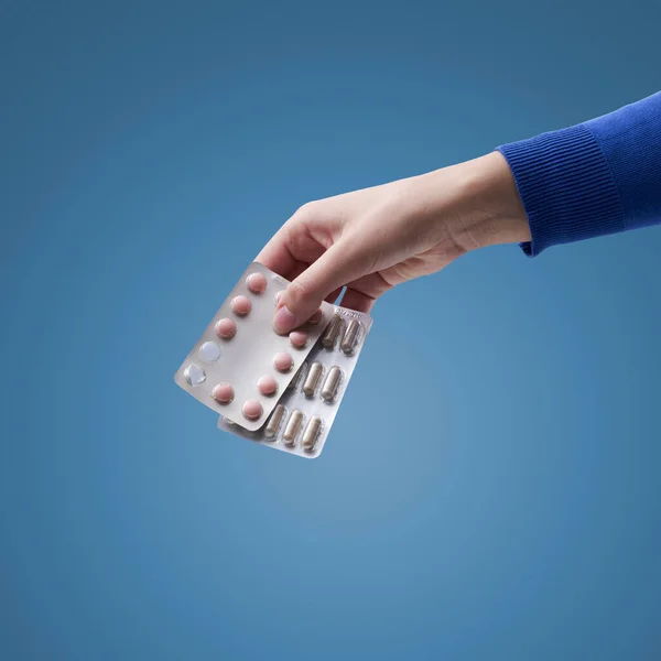 Hand holding expired medicines, isolated on blue background