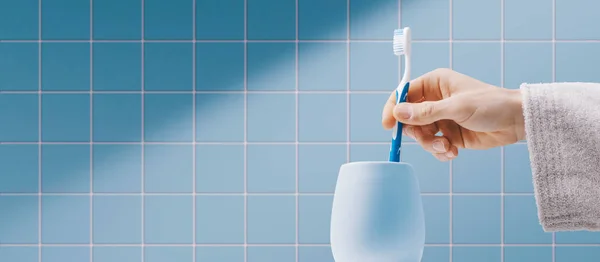 バスルームで歯を掃除する男歯ブラシホルダーに歯ブラシを入れてる — ストック写真
