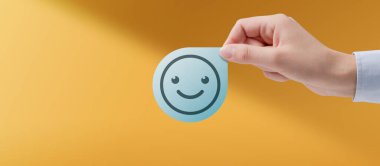 Gülümseyen ifade, pozitiflik ve mutluluk konsepti olan bir rozet tutan kadın.