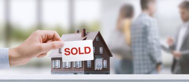 Successful home sale: a real estate agent is talking with customers in the background