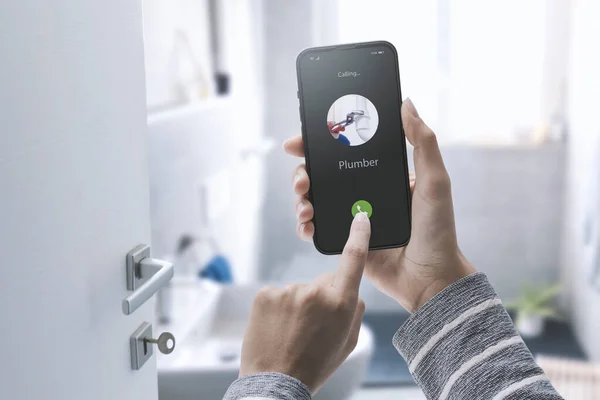 Woman Calling Plumber Her Smartphone She Has Water Leak Bathroom — Stock fotografie