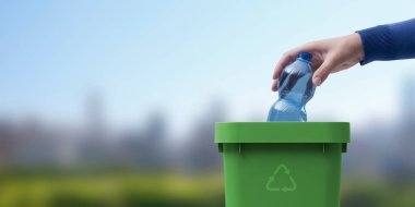 Kadın çöp kutusuna plastik şişe koyuyor, atık toplama ve geri dönüşüm konsepti ayrı, arka planda doğal manzara.