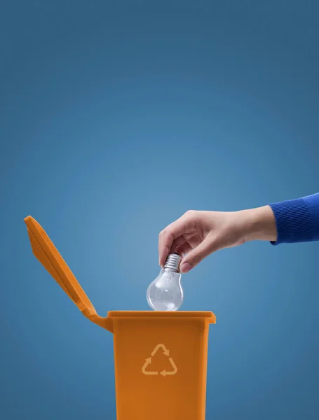 ゴミ箱に白熱電球を入れて女性 リサイクルや環境ケアの概念 — ストック写真