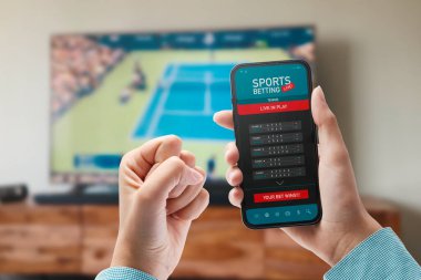 Live in-play betting app on smartphone display, a woman is betting at home and winning, POV shot
