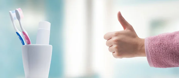 歯ブラシや歯磨き粉に親指を与えるバスローブの女性 歯科衛生の概念 — ストック写真