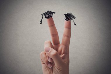 V sign gesture and sketched academic caps on fingers, university and graduation concept, copy space