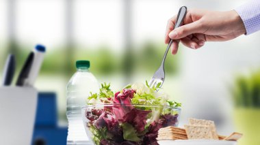 Kadın işteki öğle yemeği arasında taze sağlıklı bir salata yiyor.