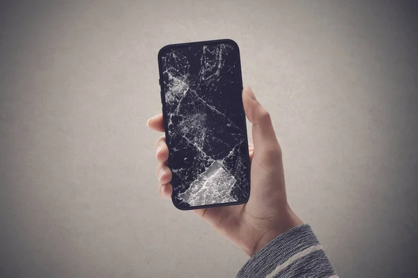 Woman holding a smartphone with cracked screen, smartphone repair service concept