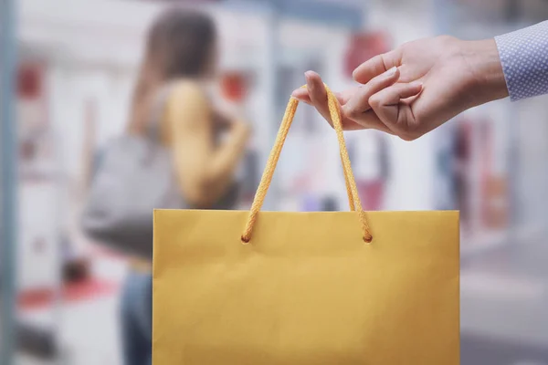 Γυναίκα Κρατώντας Μια Τσάντα Ψώνια Και Καταστήματα Στο Παρασκήνιο — Φωτογραφία Αρχείου