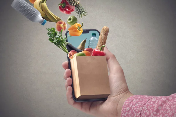 Woman Buying Groceries Online Using Her Smartphone Full Grocery Bag — Φωτογραφία Αρχείου