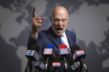 Medya tarafından sorgulanan kızgın agresif lider, mikrofonlara bağırıyor.