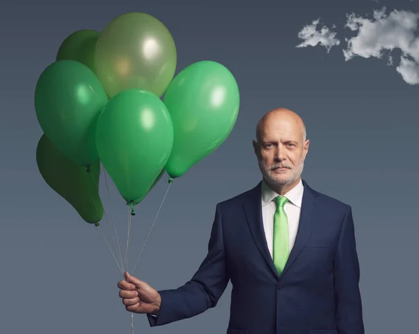 Corporate businessman holding green balloons, ecology and sustainable business concept