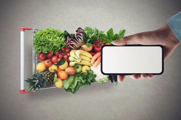 Customer Holding Smartphone Blank Screen Shopping Cart Full Fresh Vegetables — Φωτογραφία Αρχείου