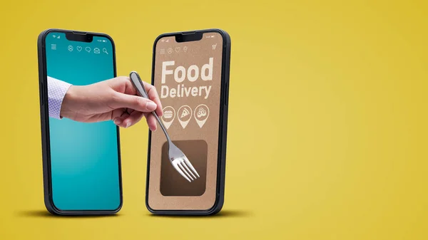 Restaurant food delivery app on smartphone, customer holding a fork and eating
