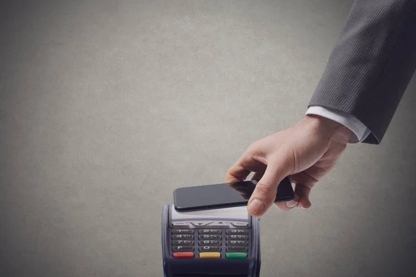 商人正在用智能手机付费 并将自己的手机放在了自动取款机上 — 图库照片