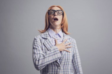 Göğsüne dokunan ve milli marşı söyleyen vatansever bir kadın, gri arka planda soyutlanmış.