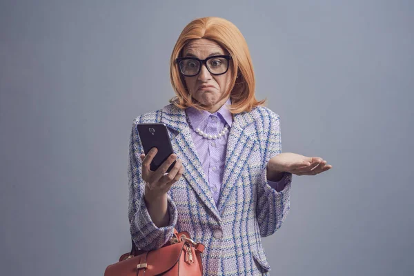 Förvirrad Kvinna Stirrar Sin Smartphone Och Skakar Axlarna — Stockfoto