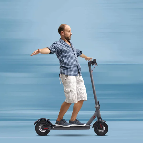 Careless man riding an electric scooter hands free, he is balacing with open arms