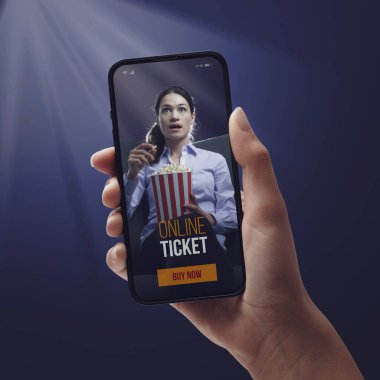 Akıllı telefonu olan bir kadın mobil uygulama kullanarak internetten sinema biletleri alıyor.