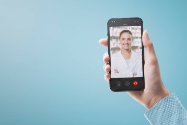 Patient holding a smartphone and video calling her online doctor, telemedicine concept, POV shot
