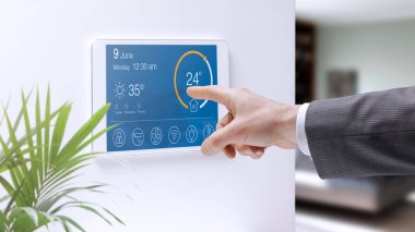 Adam ev içi ısıyı akıllı ev sistemi kontrol paneline ayarlıyor, ev otomasyon konsepti
