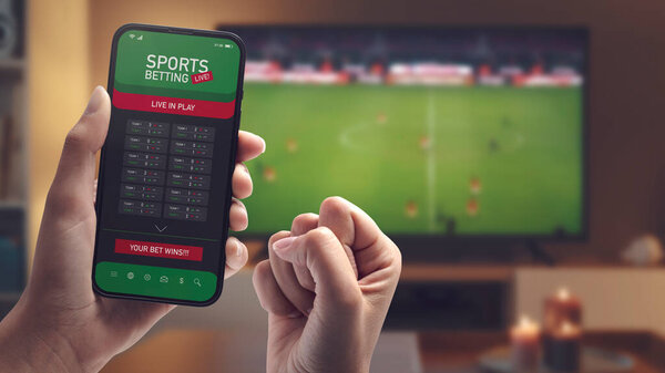 Live in-play betting app on smartphone display, a woman is betting at home and winning, POV shot