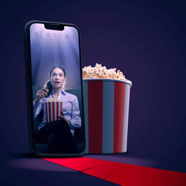 Woman watching movies on a smartphone screen, popcorn and red carpet, online movies and cinema app concept