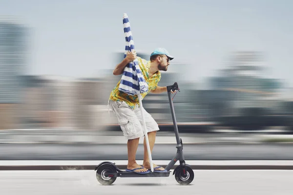 電気スクーターに乗ってビーチの傘を持っている男は 彼はビーチに行く — ストック写真