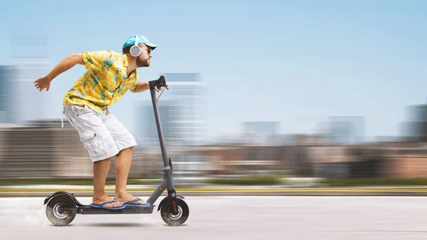 カラフルなビーチシャツを着て 高速環境に優しい電動スクーターに乗ってクールなスタイリッシュな男 背景の都市 — ストック写真