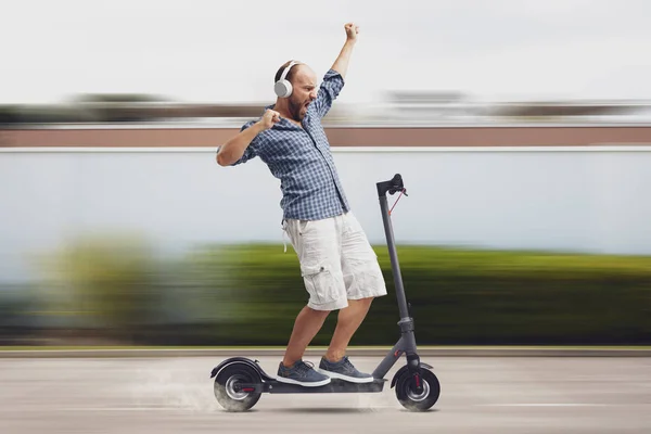 Neşeli Adam Arka Planda Elektrikli Scooter Sürerken Müzik Dinleyip Dans — Stok fotoğraf