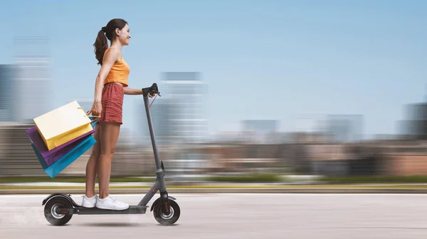 Jovem Feliz Carregando Muitos Sacos Compras Montando Uma Scooter Elétrica — Fotografia de Stock