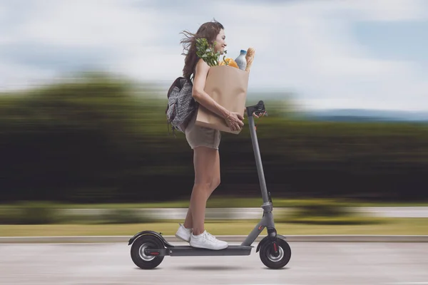 Alışveriş Poşeti Taşıyan Hızlı Elektrikli Scooter Kullanan Genç Bir Kadın — Stok fotoğraf