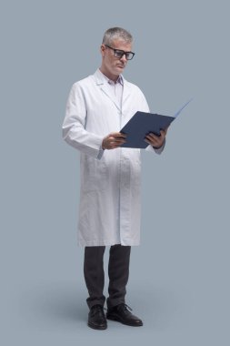 Profesyonel doktor ayakta duruyor ve tıbbi kayıtları, sağlık ve tıp konseptini kontrol ediyor