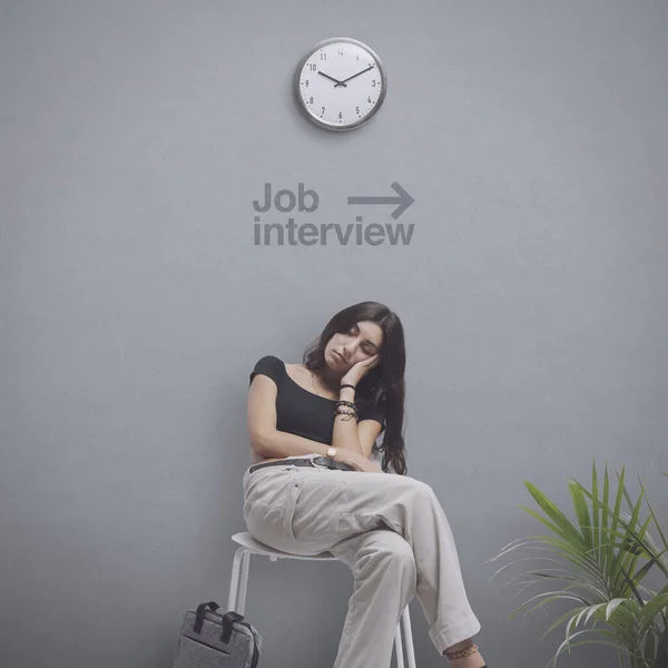 Young bored student sitting on a chair and waiting for a job interview, she is falling asleep