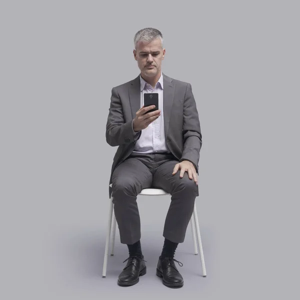 사업가가 의자에 앉아서 스마트폰으로 온라인을 연결하는 — 스톡 사진