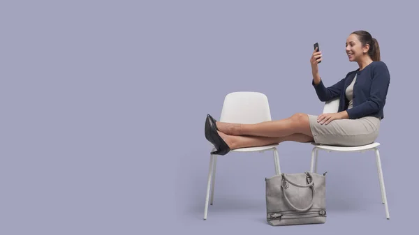 Грудаста Жінка Сидить Ногами Кімнаті Очікування Спілкується Своїм Смартфоном — стокове фото