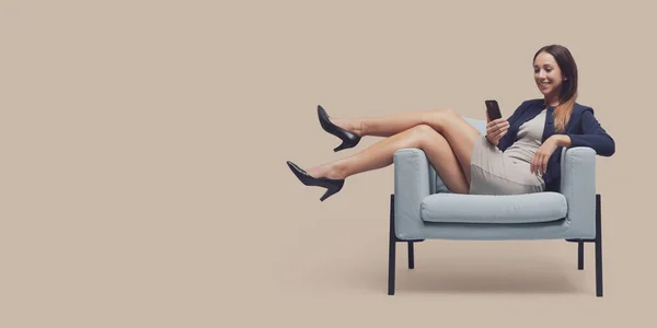 足を組んで座っているビジネスマンの女性と彼女のスマートフォンでビデオ通話 — ストック写真