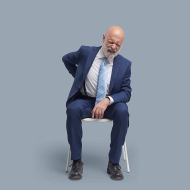 Sırtı ağrıyan hayal kırıklığına uğramış iş adamı, bir sandalyede oturuyor.