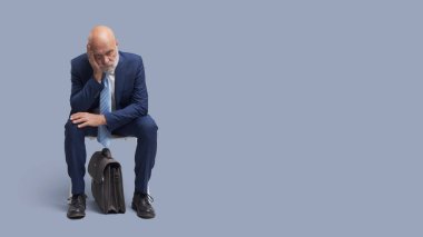 Sıkılmış kurumsal iş adamı bir sandalyede oturup iş görüşmesini bekliyor, boş bir fotokopi odası.